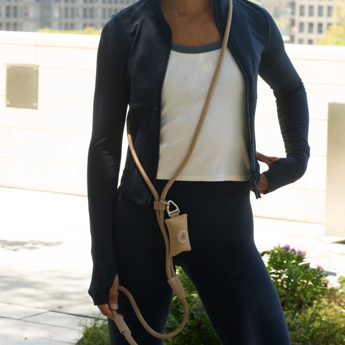 Close-up of a dog owner wearing the Premium Brown hands-free leash across the body with an attached accessory poop bag holder.
